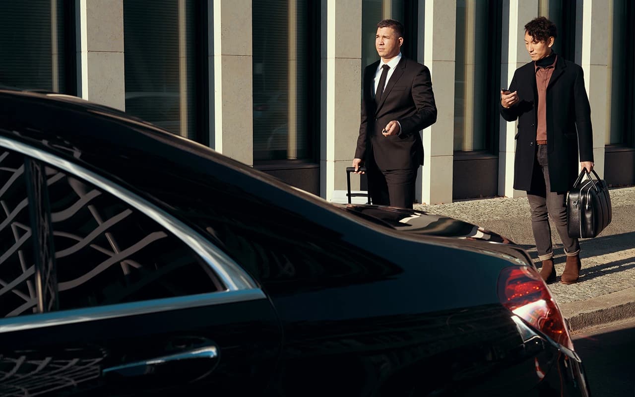Passengers waiting by a luxury vehicle
